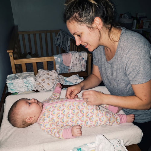Mom changing her baby on a changing table in the Sweet Sleep Pastel Rainbows Zippy