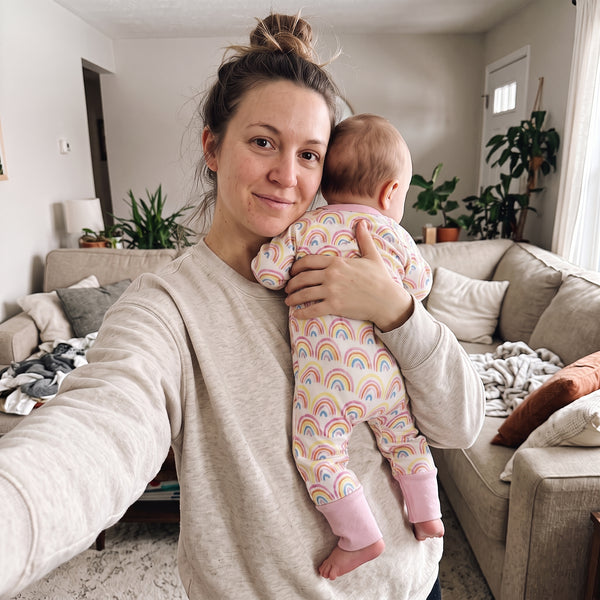 Mom holding her baby dressed in the Sweet Sleep Pastel Rainbows Zippy at home