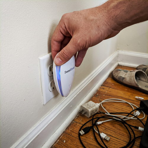 Hand plugging a PestPro ultrasonic pest repeller into a baseboard outlet