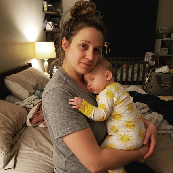 Tired mother holding her sleeping baby in Sweet Sleep Sunshine Zippy pajamas