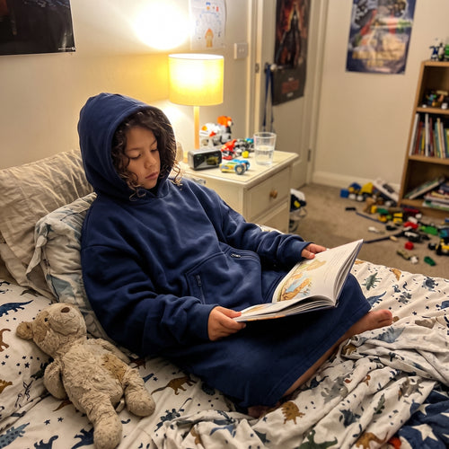 Child reading in bed wearing the Sweet Sleep Kids Hug Hoodie