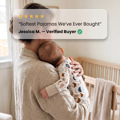 Parent holding a baby in the Luna Neutral Zippy footie by a crib