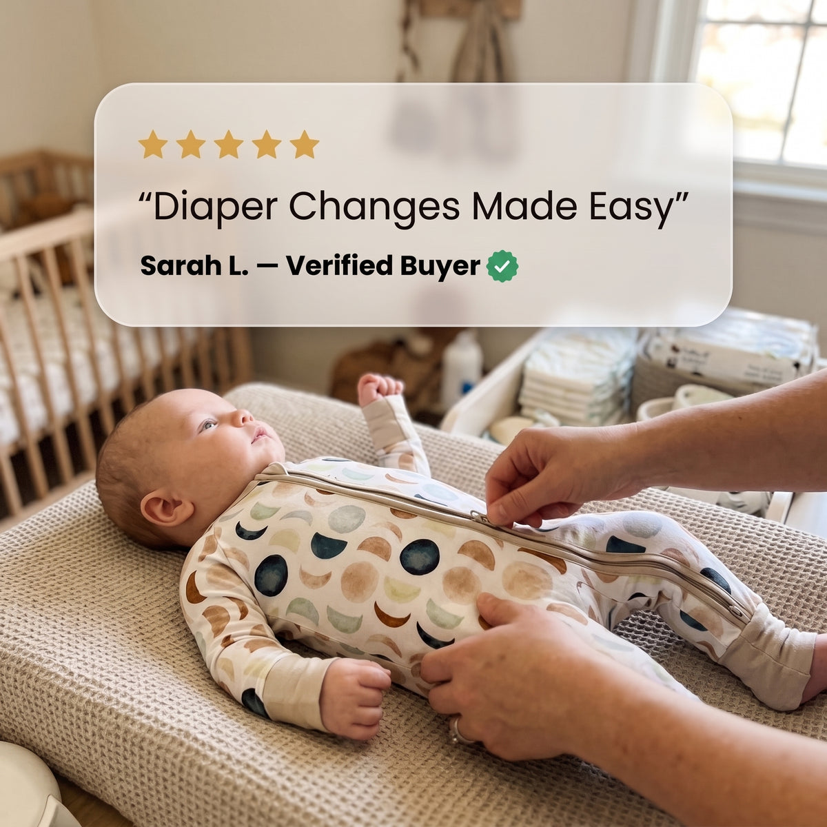 Parent zipping a baby into the Luna Neutral Zippy footie on a changing pad