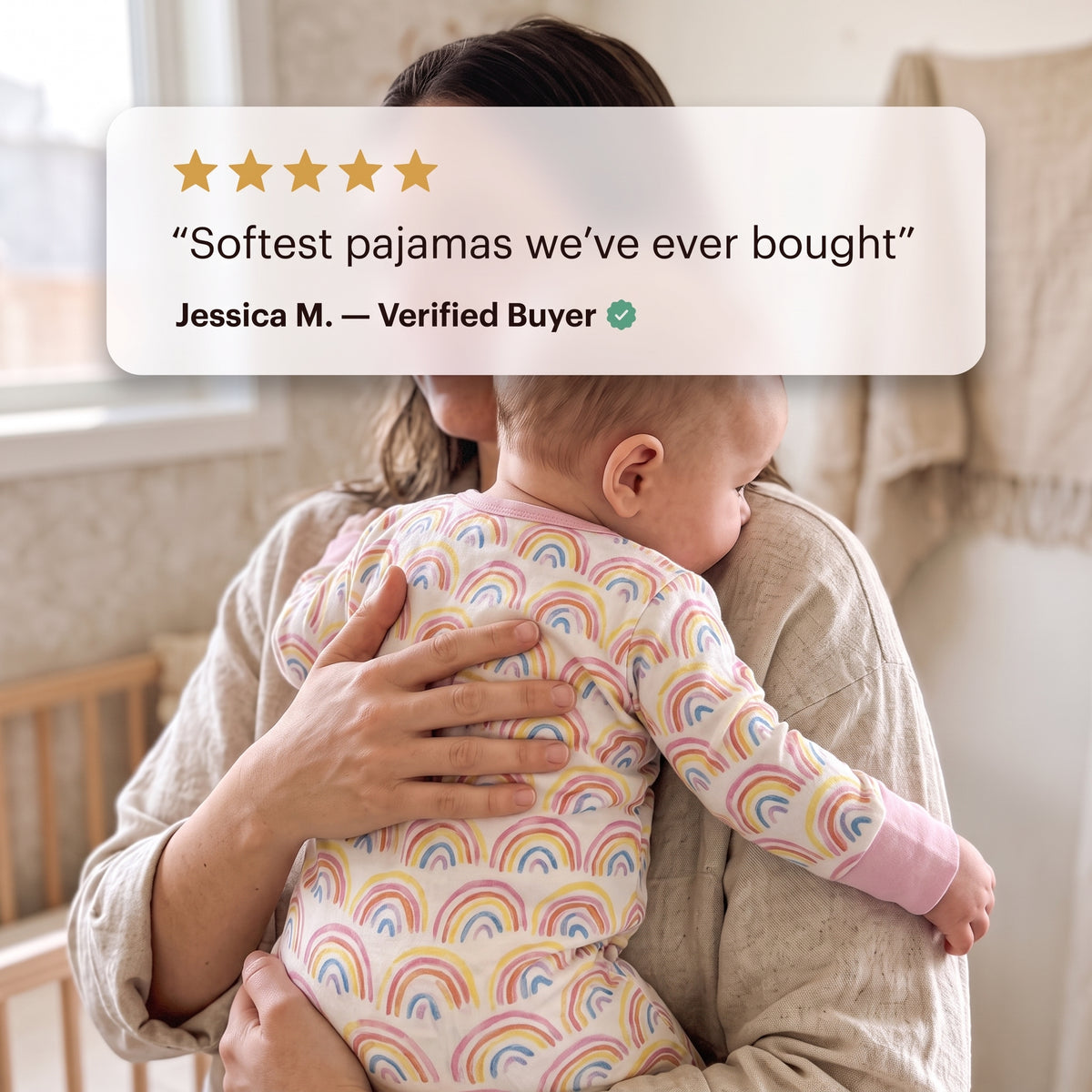 Parent holding a baby in the Sweet Sleep Pastel Rainbows Zippy footie with a customer review