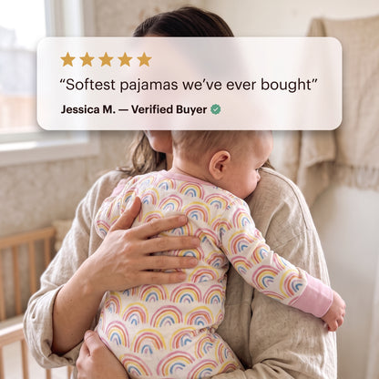 Parent holding a baby in the Sweet Sleep Pastel Rainbows Zippy footie with a customer review