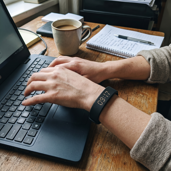 Hands typing on a laptop with the Sweet Sleep Premium Wrist Alarm on the wrist